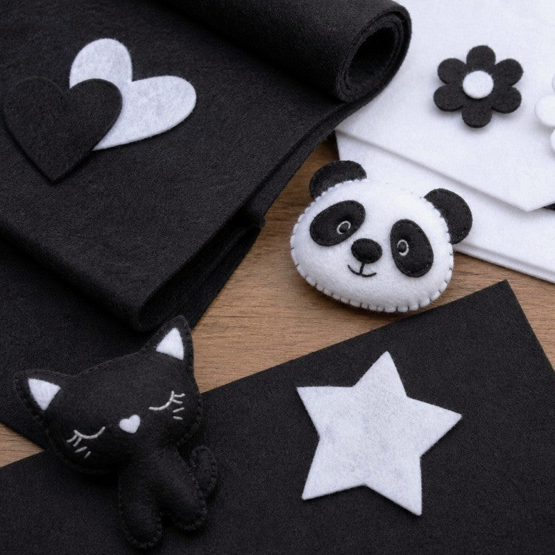 Filz-Bastelmaterialien in schwarz und weiß auf einem Holztisch