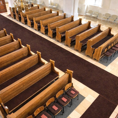 Innenraum einer Kirche mit Holz-Kirchenbänken und Stühlen, die braune Filzauflagen haben.